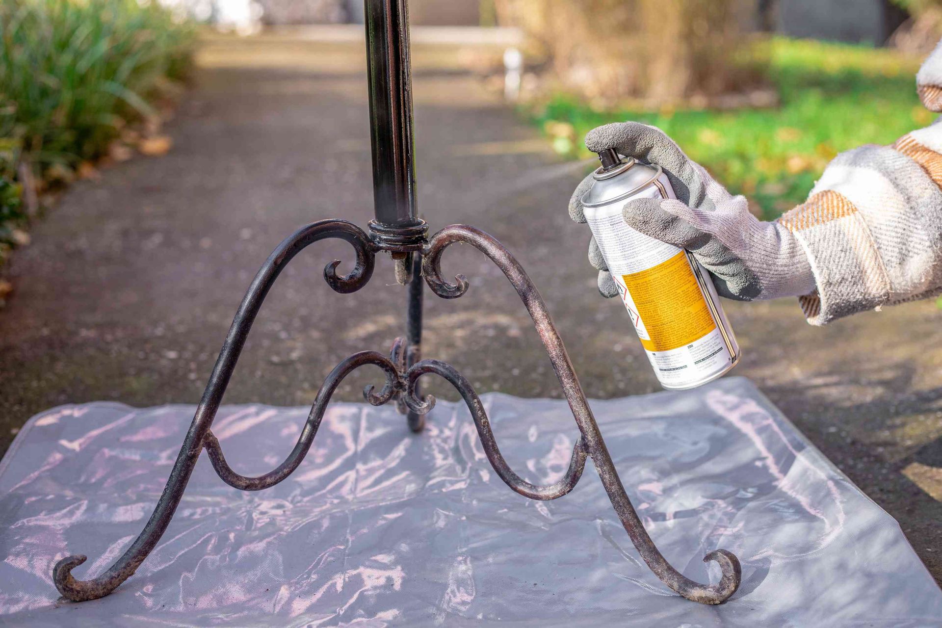 A person is spraying paint on a wrought iron table.