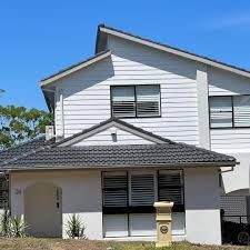 A white house with a black roof and a mailbox in front of it.
