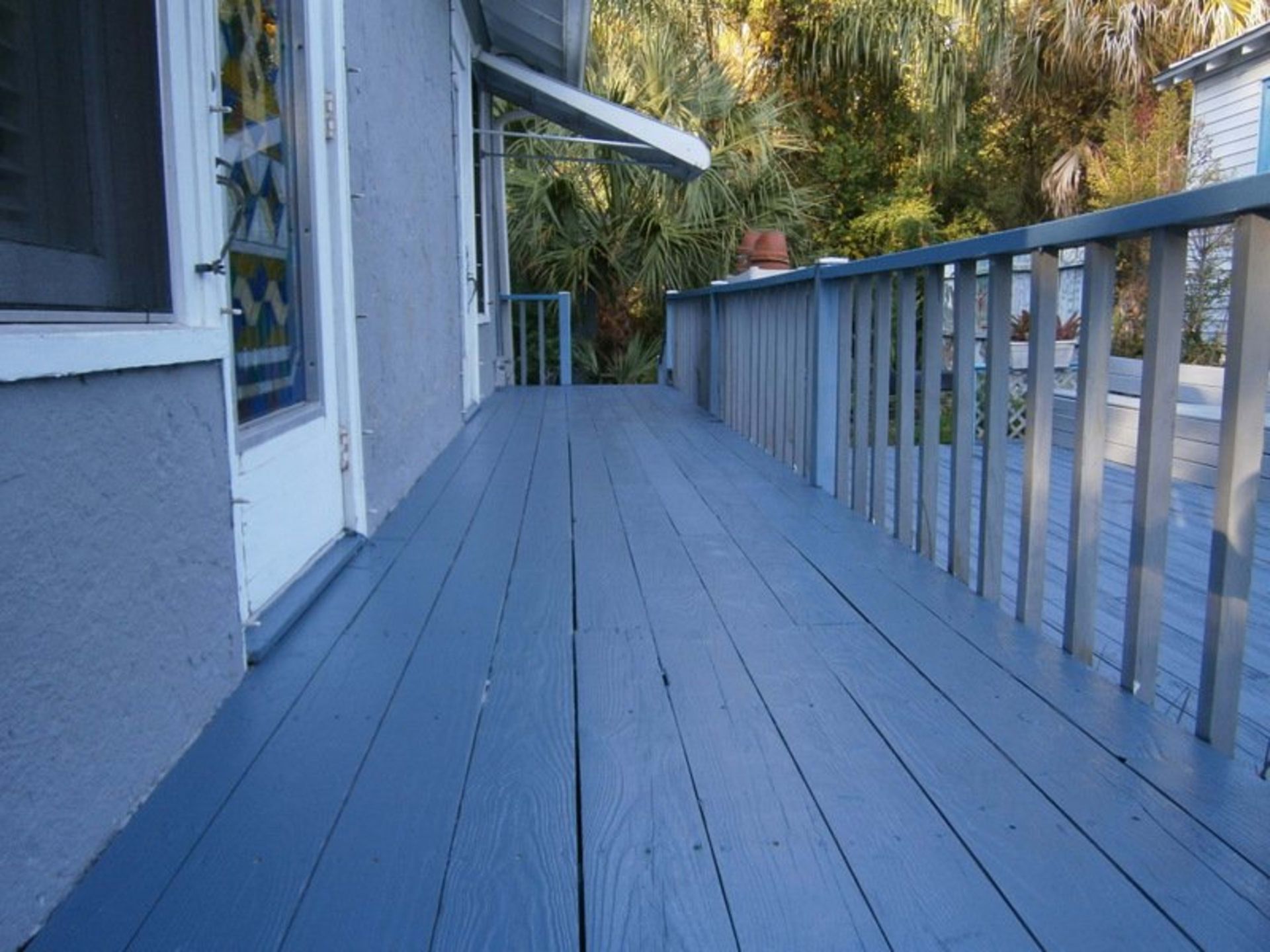 A blue deck with a metal railing and a screen door