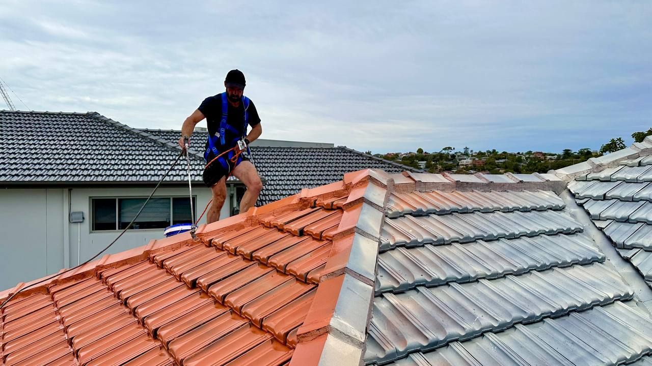 A man is standing on top of a tiled roof.