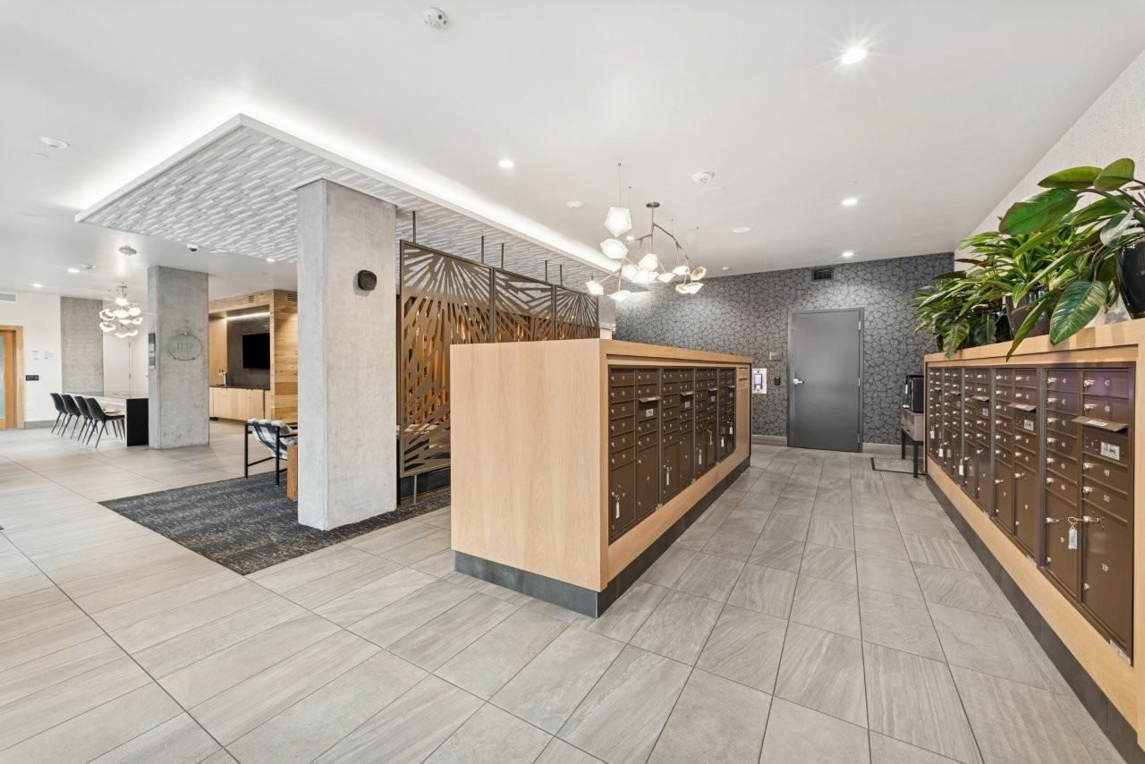 Apartment building lobby with mailboxes, tiled floor, and decorative lighting.