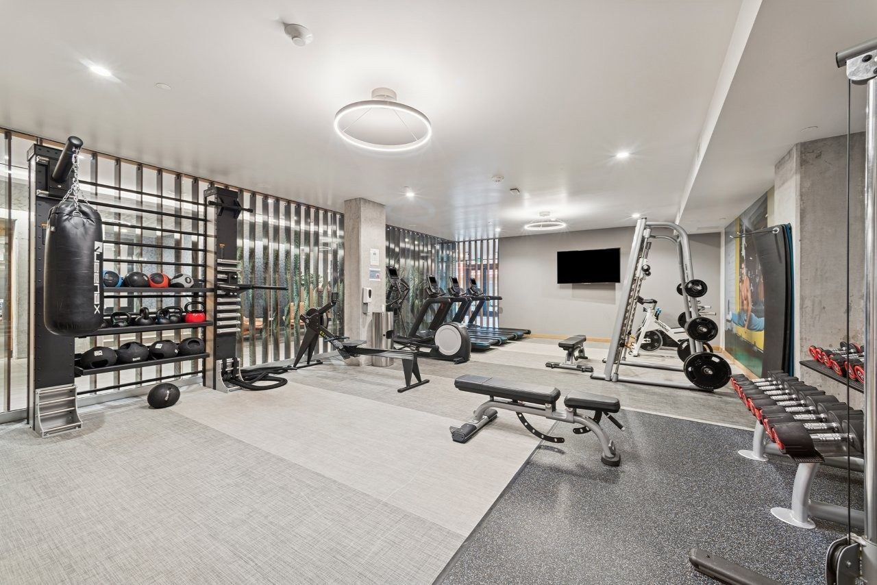 Gym with weight racks, punching bag, treadmills, weight bench, and dumbbells.