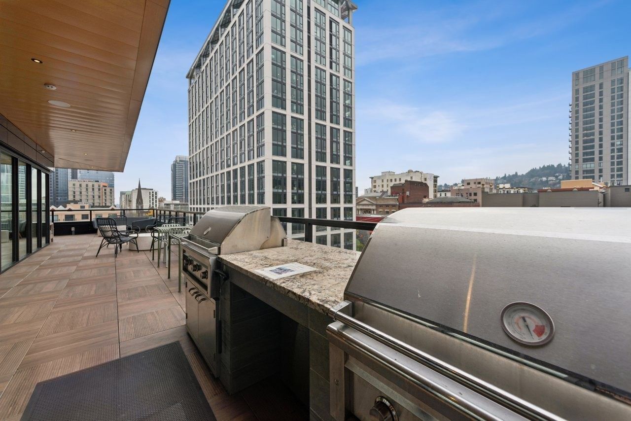 Outdoor balcony with stainless steel grills, cityscape background.