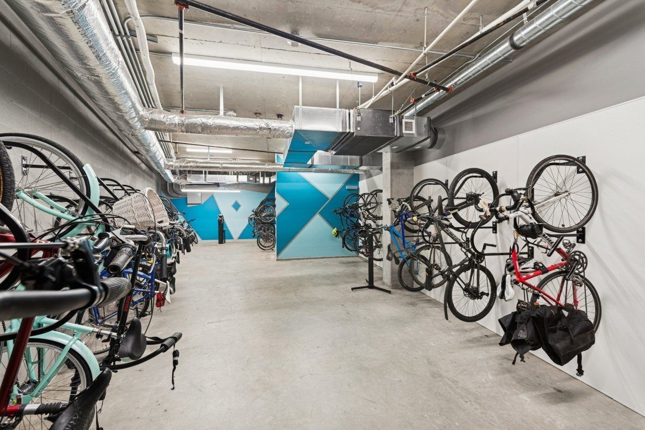 Bike storage room with bikes on racks and wall mounts, concrete floor, white and blue accent wall.