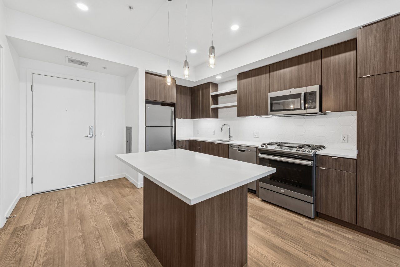 Modern kitchen with dark wood cabinets, stainless steel appliances, and white countertop island.