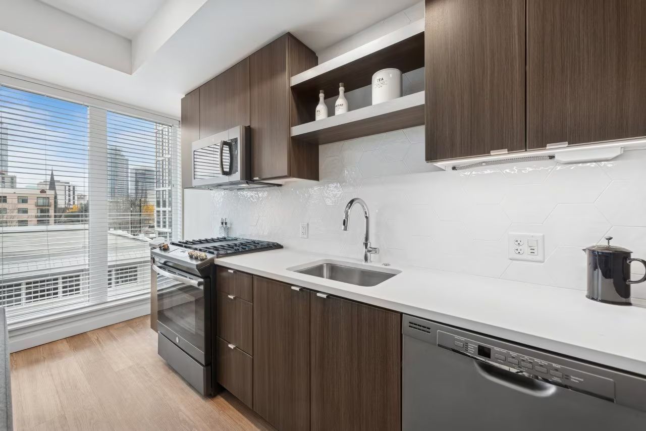 Modern kitchen with dark wood cabinets, stainless steel appliances, and city view.