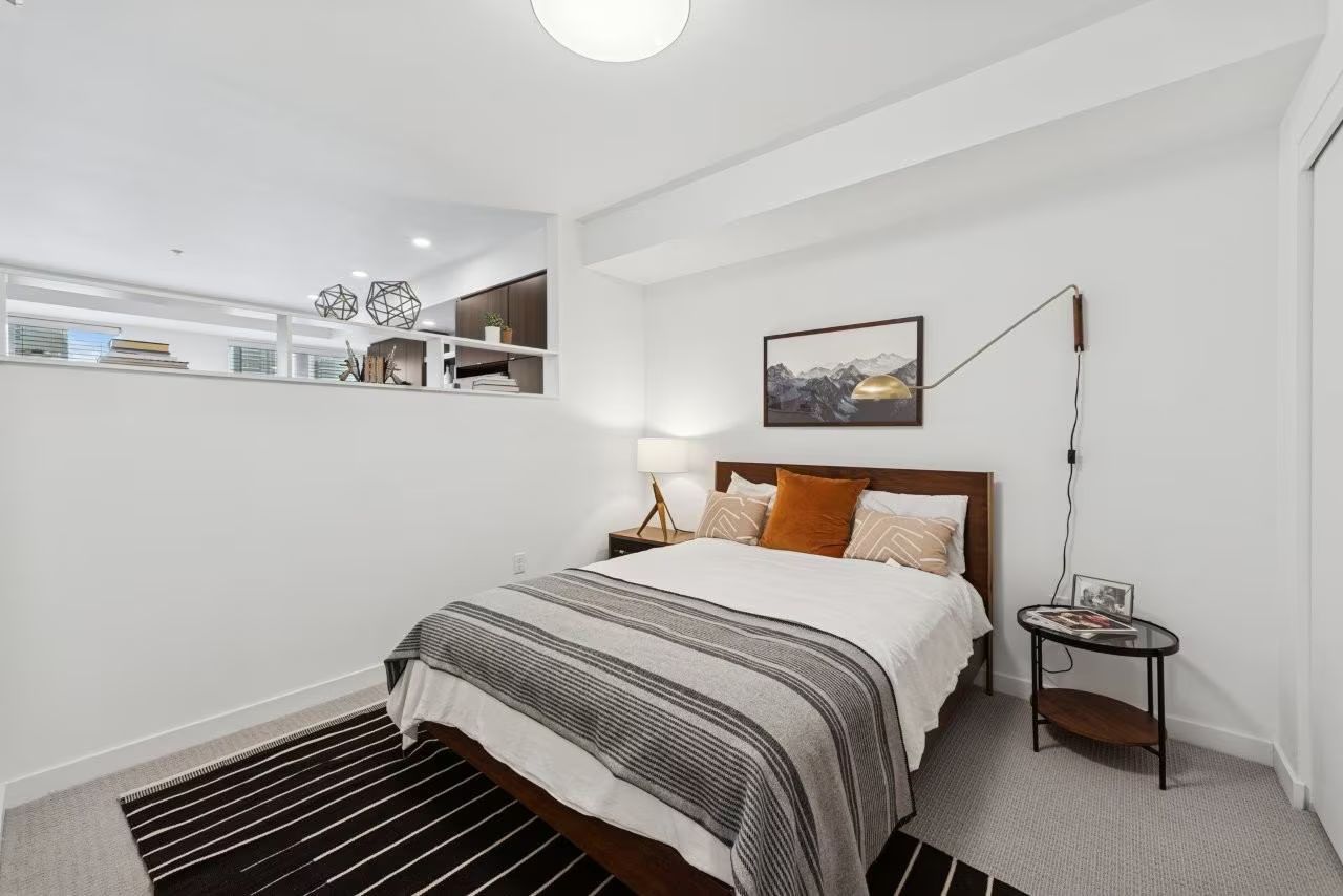 Bedroom with bed, rug, small table, and a wall art.