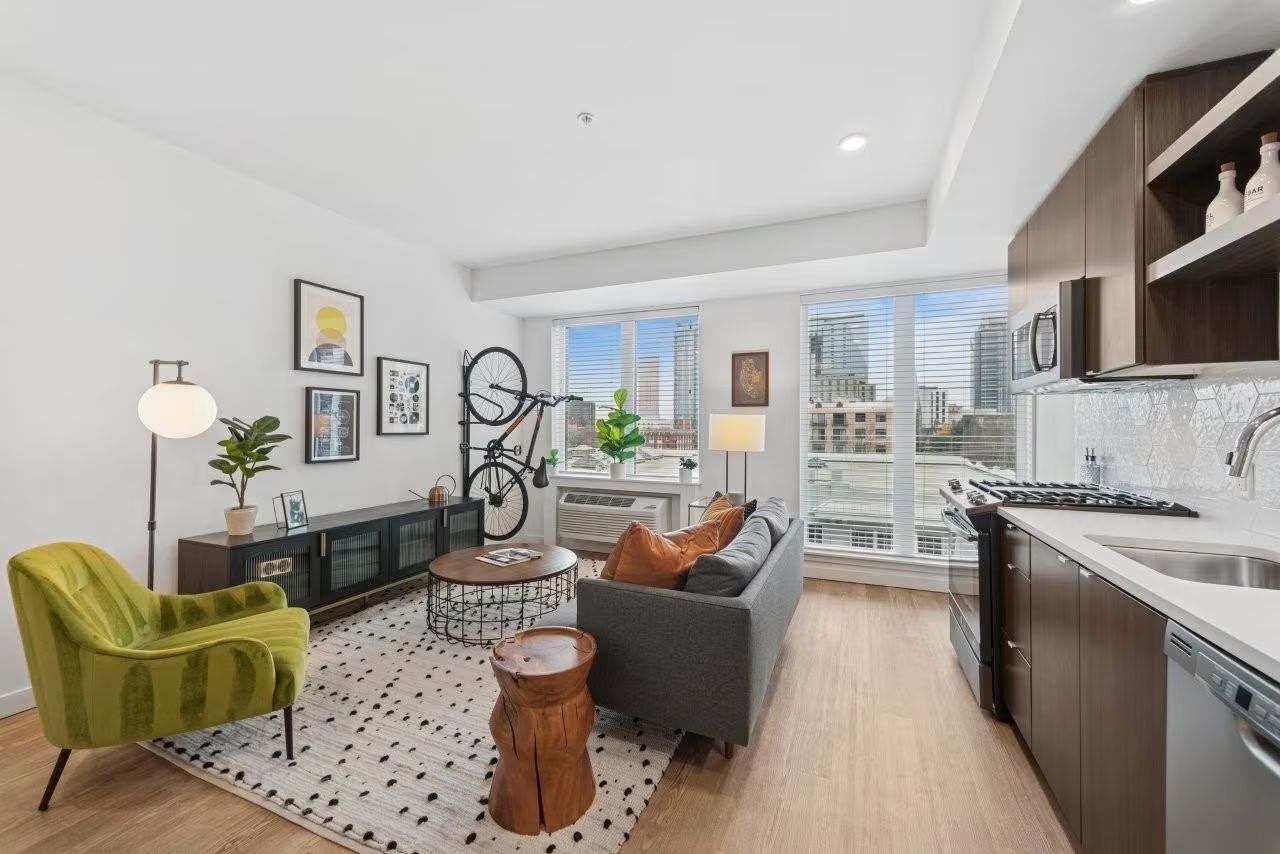 Modern living room with furniture, decor, and large windows with city view.