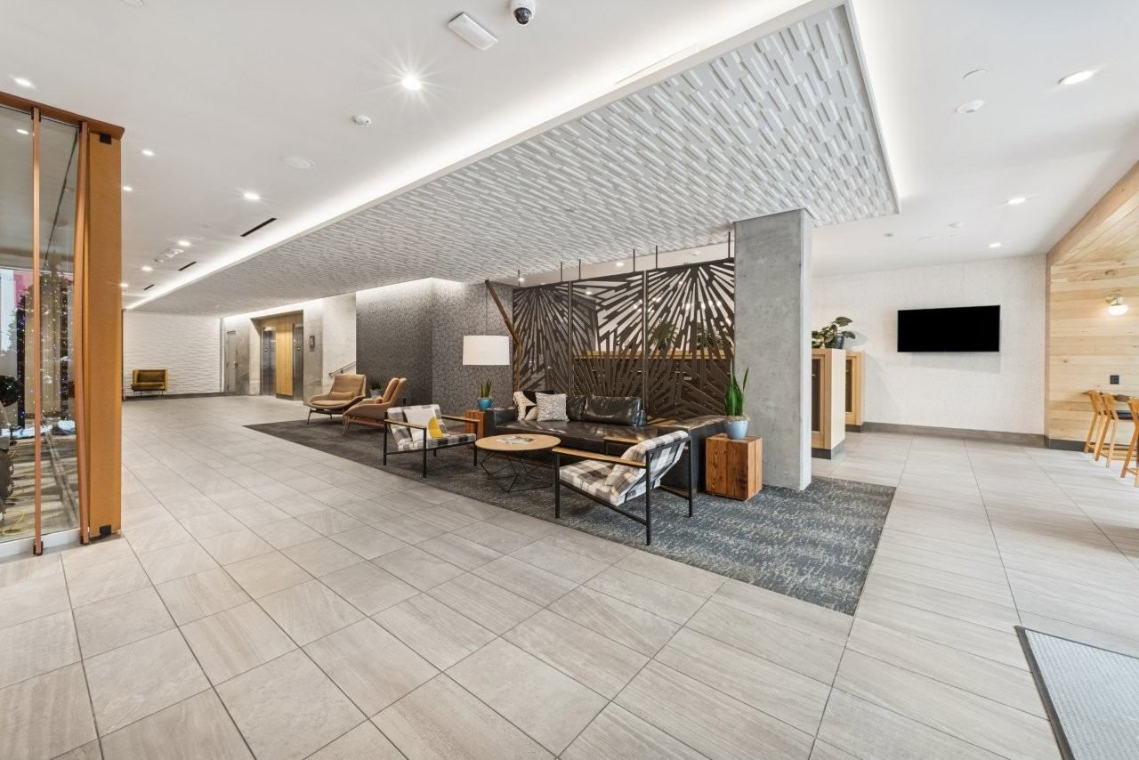 Spacious lobby with seating area, elevators, and decorative wall. Neutral colors with modern design.