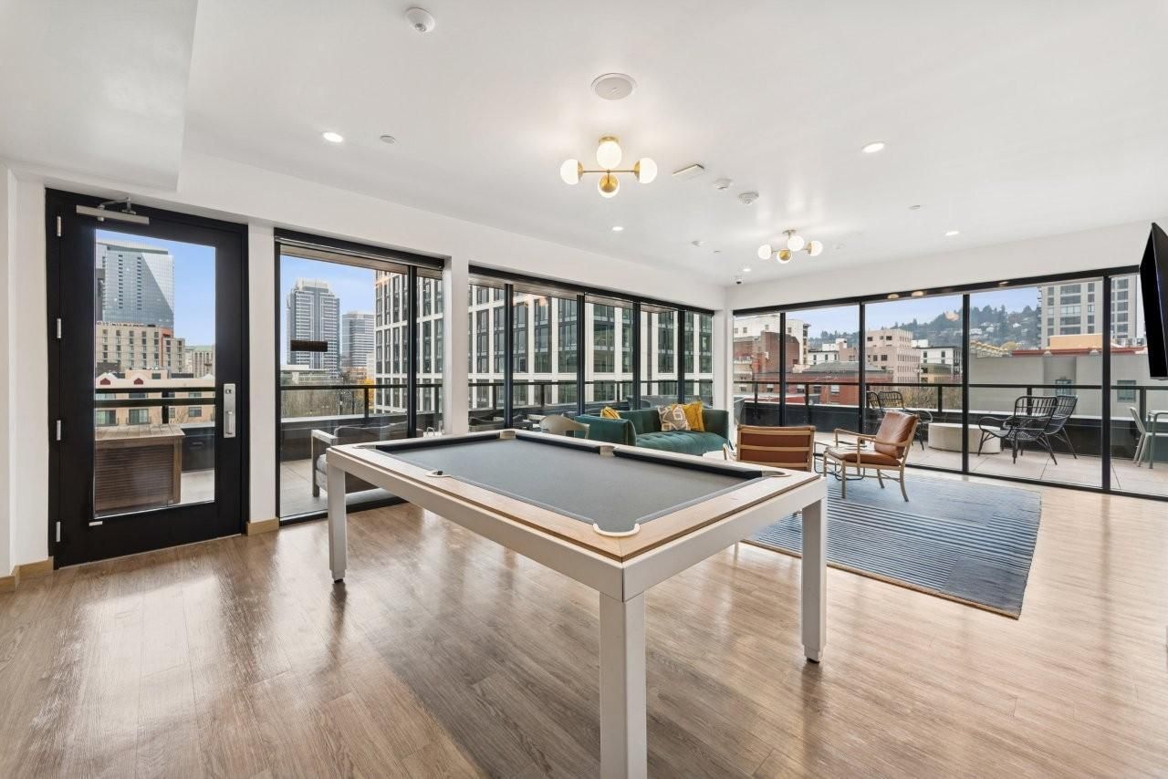 Spacious room with pool table, large windows overlooking cityscape, and seating area.