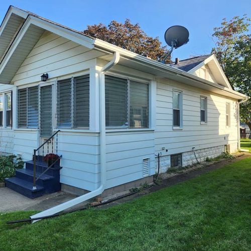 White house with blue steps and a satellite dish on the roof, surrounded by green grass.