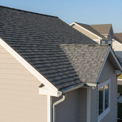 Two gray-shingled house roofs with white trim and a gutter, viewed from above. Two gray-shingled house roofs with white trim and a gutter, viewed from above.