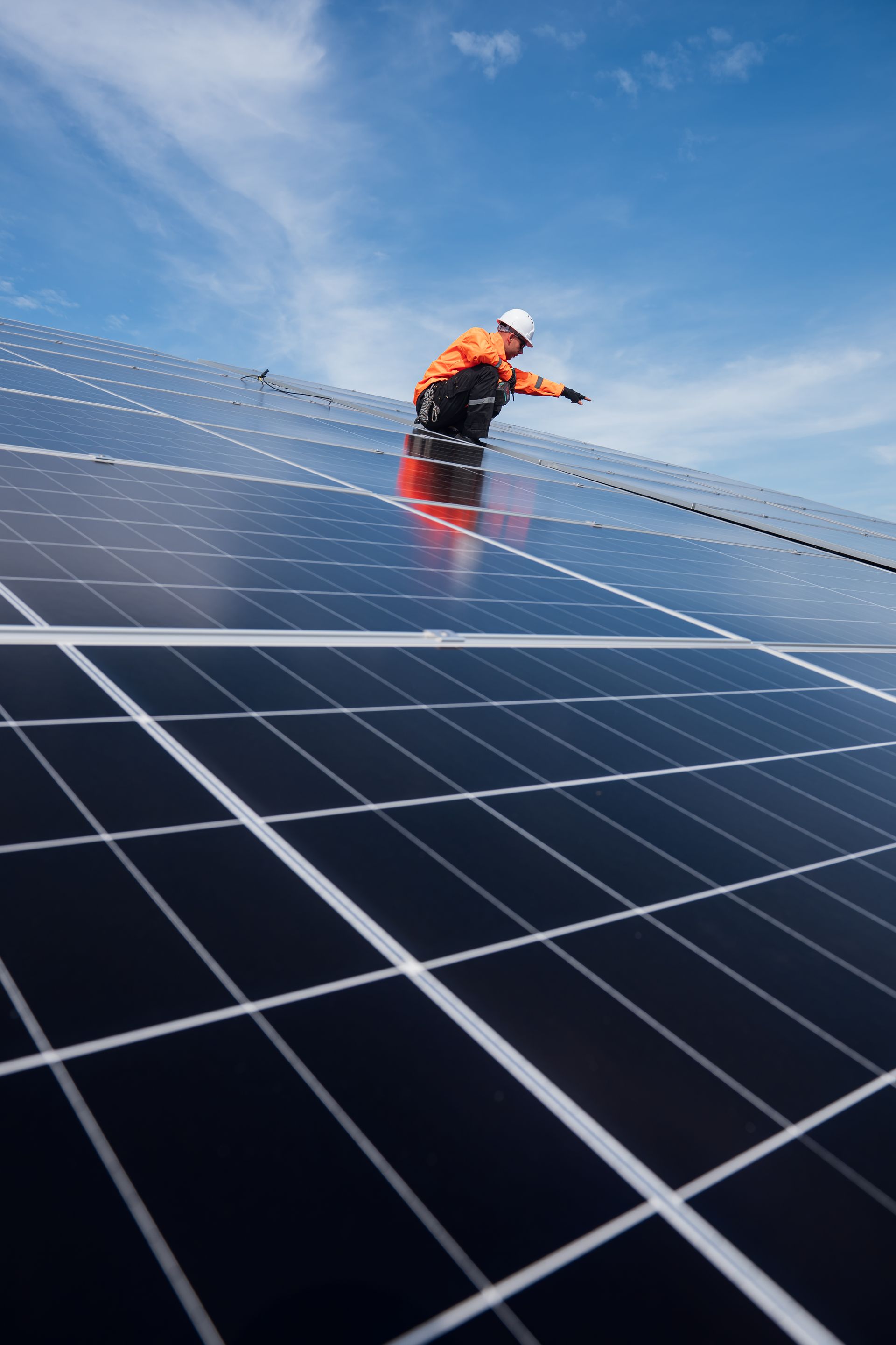 Worker cleaning solar panels on a rooftop under a blue sky