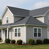 Two-story beige house with gray roof, white trim, and small front porch in a suburban yard