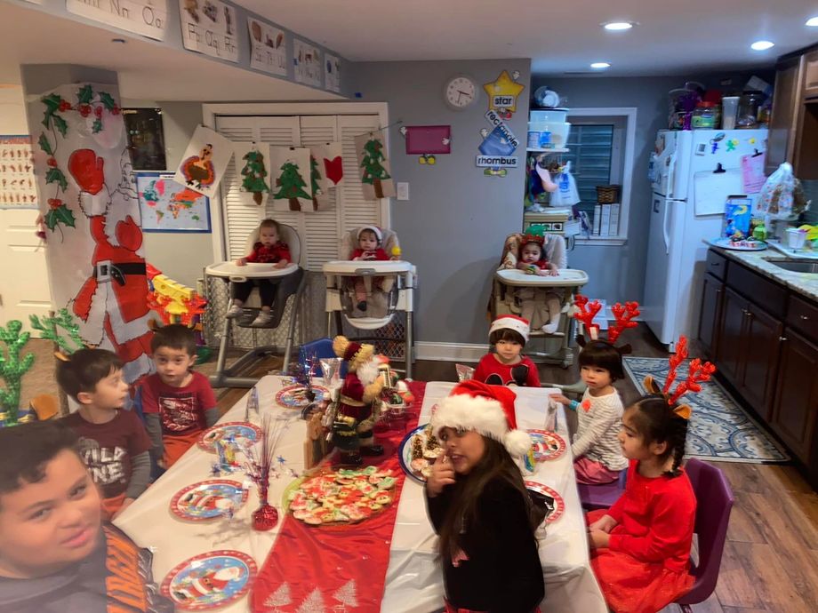 Children seated at a holiday table in a decorated room with Christmas crafts and decorations