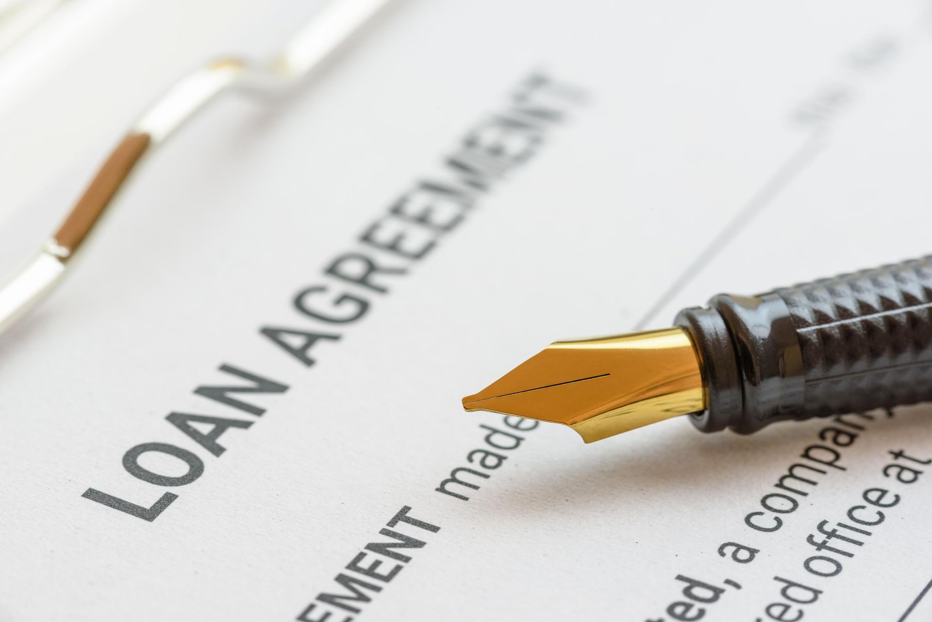 A fountain pen is sitting on top of a loan agreement.