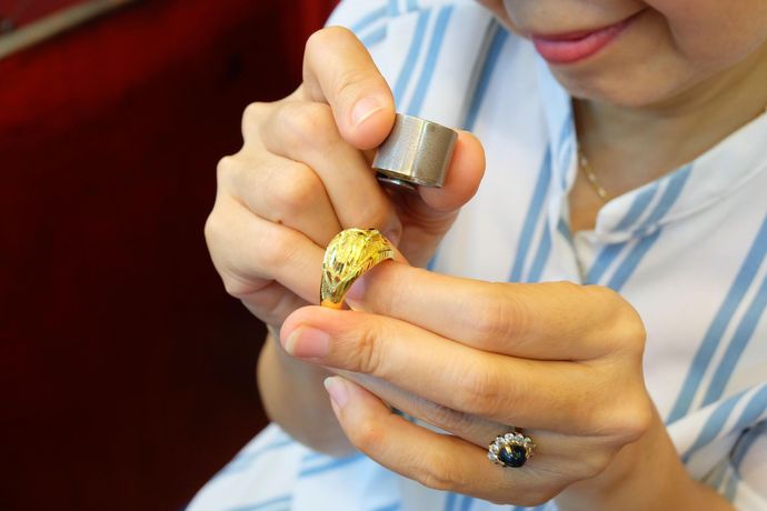 A woman is looking at a ring with a magnifying glass.