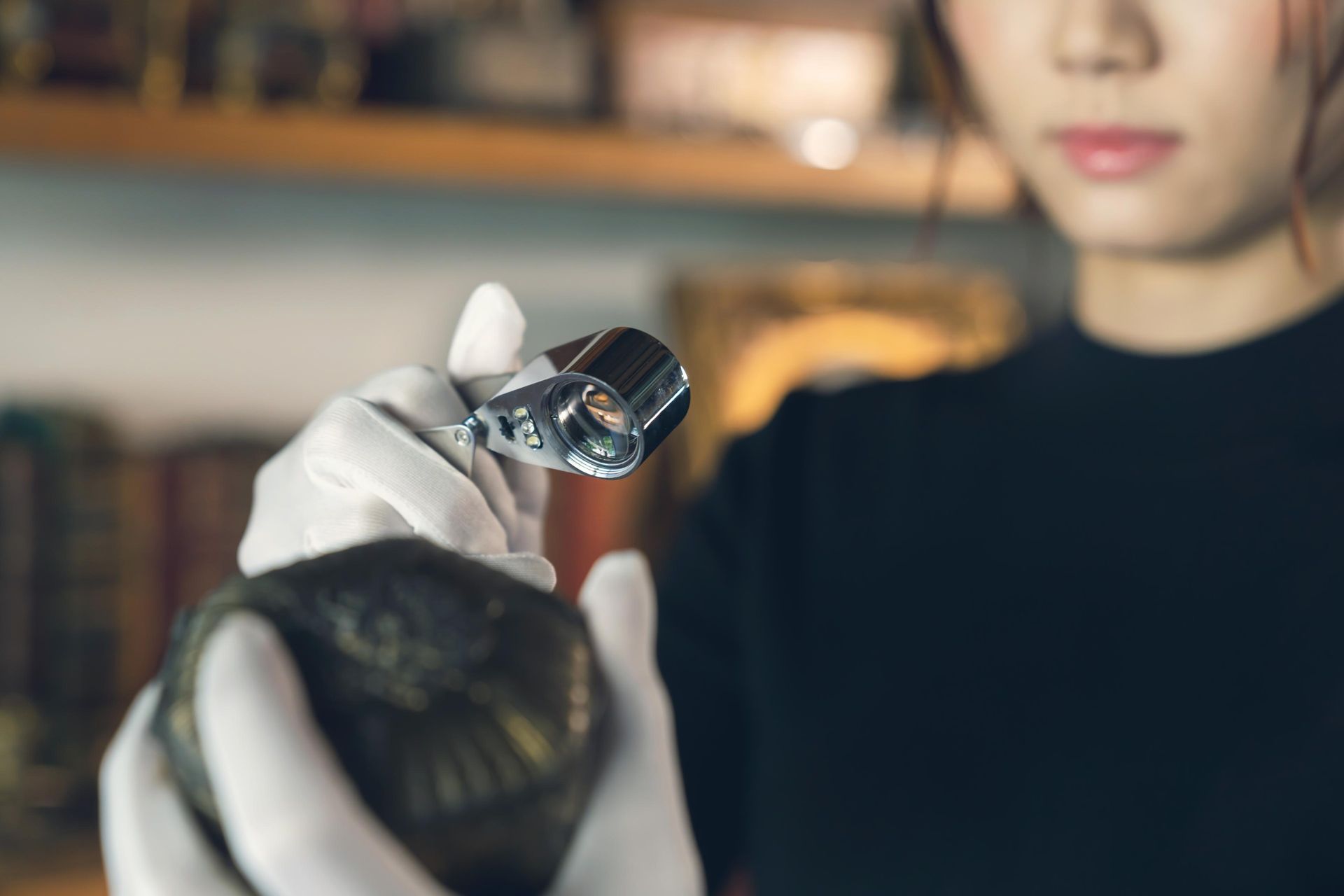 A woman is holding a magnifying glass over a rock.