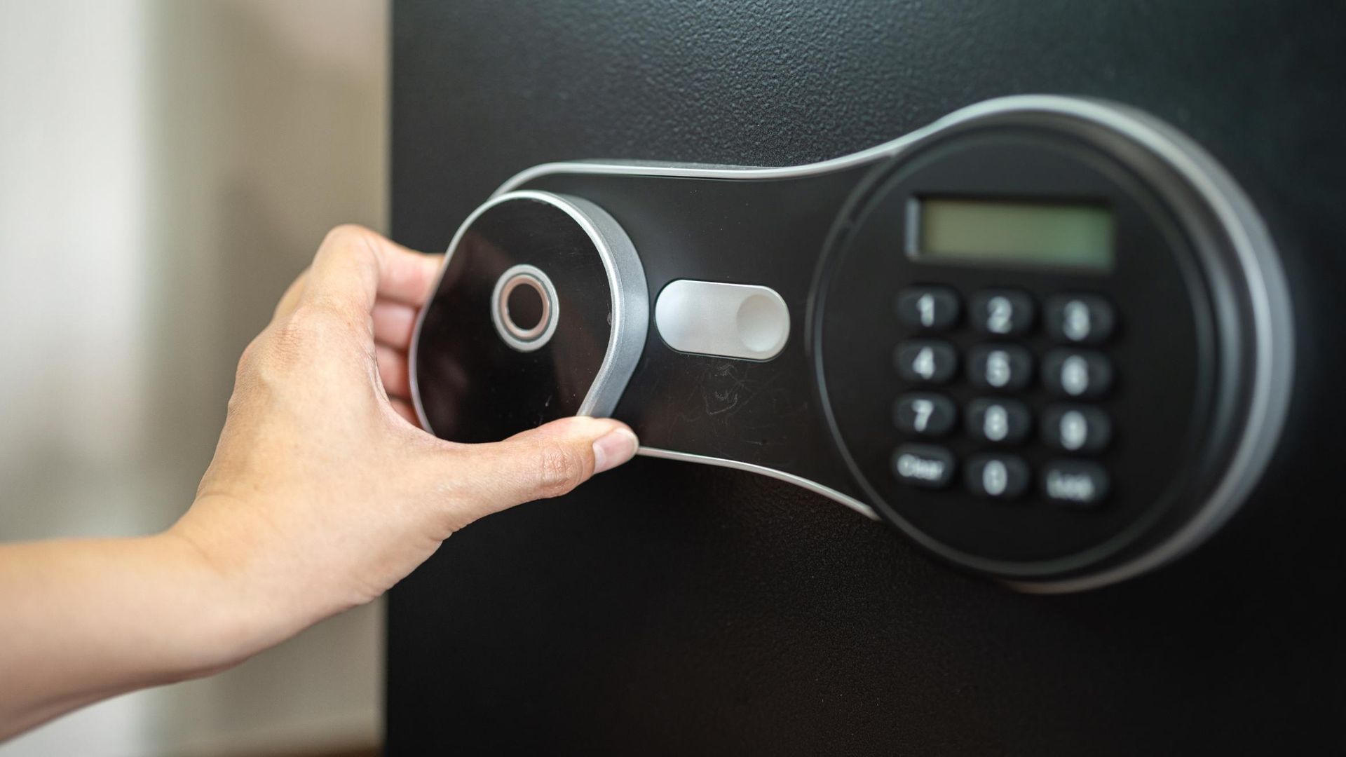 A person is opening a digital safe with a key.