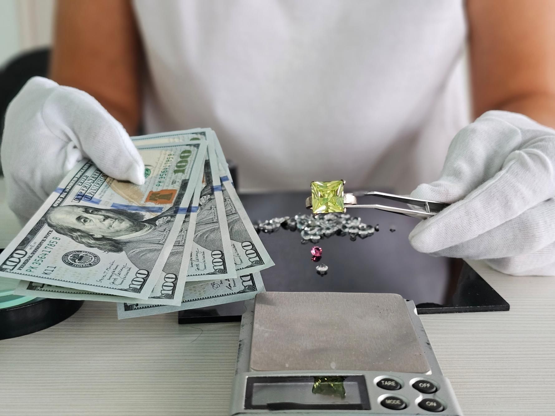 A person is holding a pile of money next to a scale.