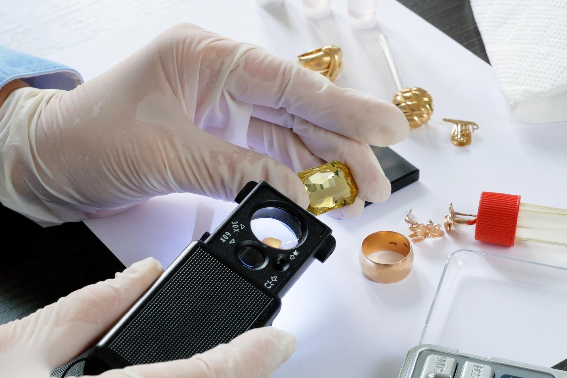 A person is holding a magnifying glass over a gold ring.