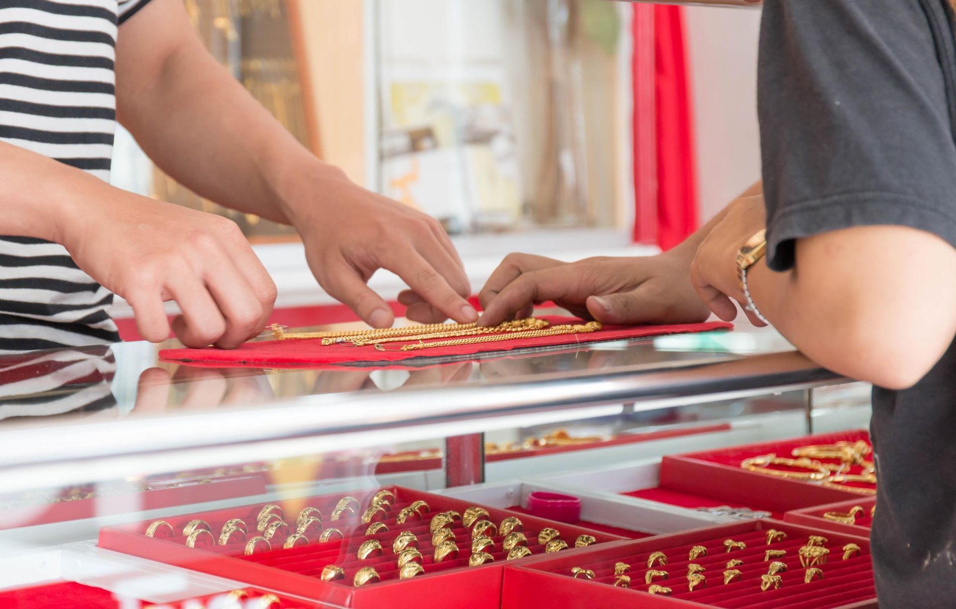 A man and a woman are looking at gold jewelry in a jewelry store.