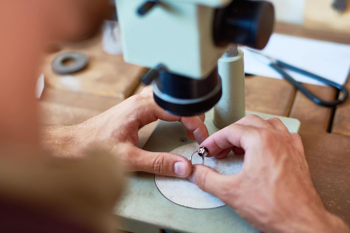 A person is looking through a microscope at a ring.