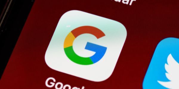 A close-up view of the Google app icon on a mobile device screen next to a portion of the Twitter app icon.