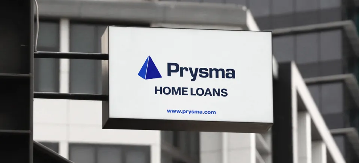 A white rectangular sign hanging against a building reads 