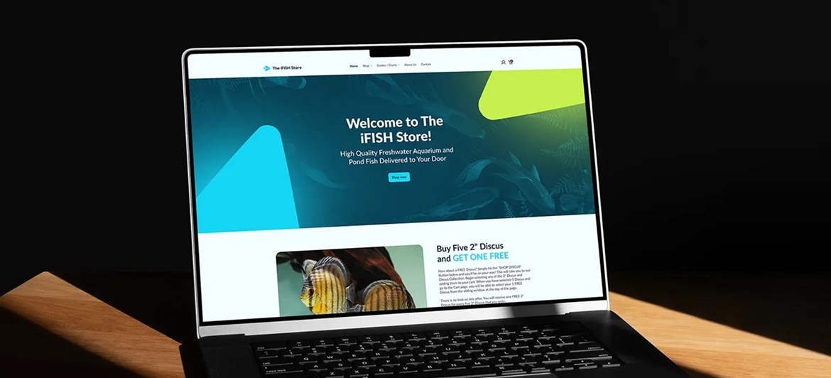 A laptop screen displays a colorful website with a blue, yellow, and green theme, sitting on a wooden surface.