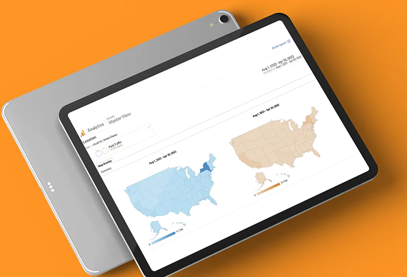 A tablet displaying a Google Analytics dashboard with two U.S. maps showing regional data against an orange background.