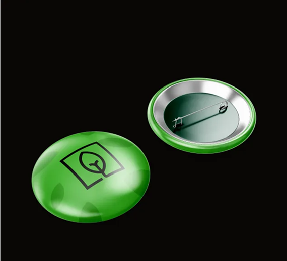 Two green circular pin-back buttons on a black background; one shows a black leaf icon inside a square.