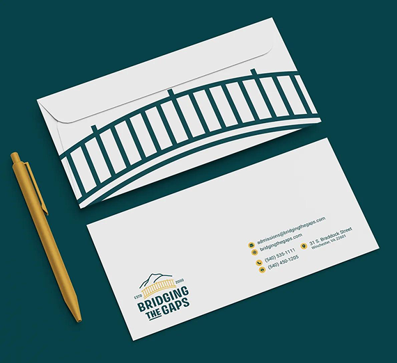 A mockup of a branded envelope with a bridge graphic and contact details, accompanied by a gold pen on a dark green background.