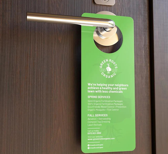 A Green Roots Organic lawn care service door hanger hangs from a modern door handle.