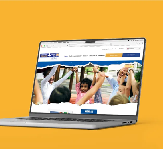 A silver laptop on a solid yellow background displays a website homepage featuring a group of children raising their hands.
