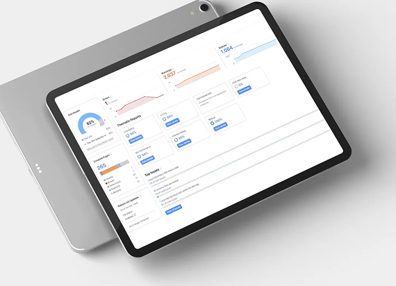 A digital tablet displaying a business analytics dashboard with data charts, graphs, and summary statistics on a white desk.
