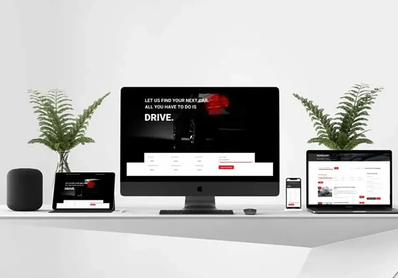 A desktop monitor, laptop, tablet, and smartphone displaying a car dealership website, arranged on a white desk with plants.