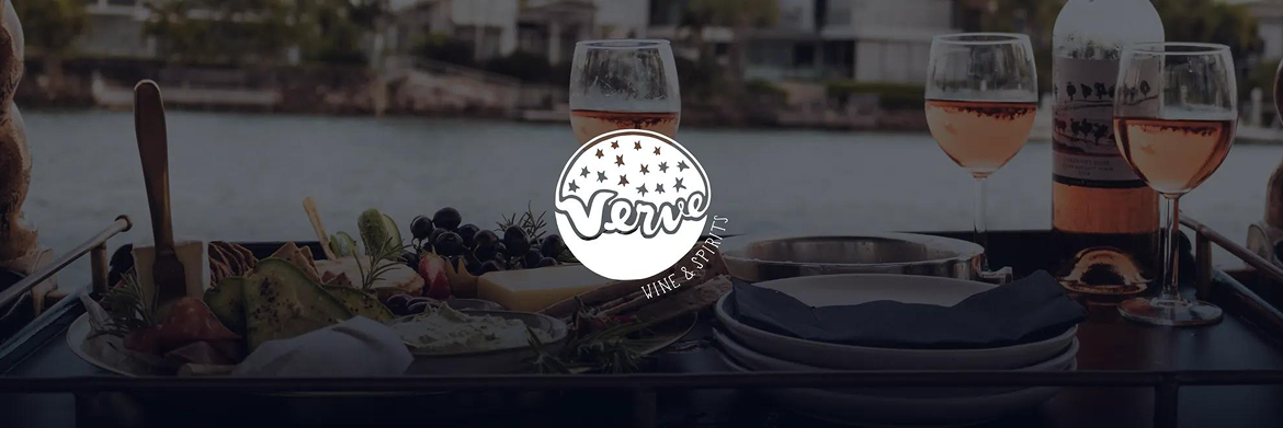 A table with a charcuterie board, wine glasses, and a wine bottle set against a blurred waterfront backdrop.