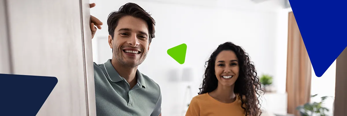 A smiling couple stands together in a bright, modern interior, looking toward the camera.