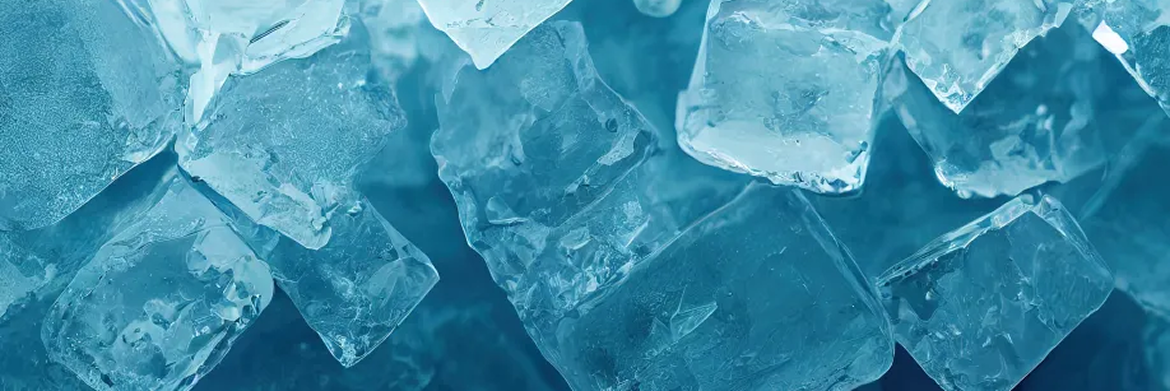 A close-up view of numerous translucent ice cubes scattered against a dark, cool-toned blue background.