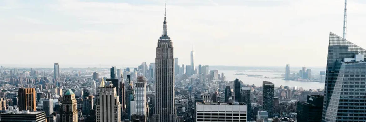 Panoramic view of the New York City skyline, featuring the Empire State Building as the central focal point.