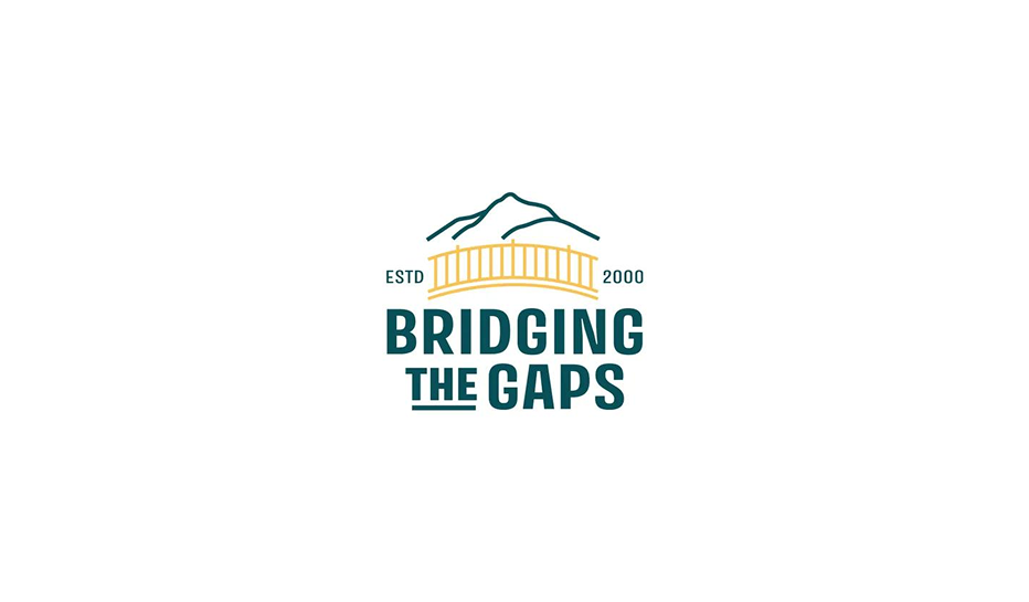 Logo for Bridging the Gaps with a mountain outline, a bridge illustration, and text on a white background.