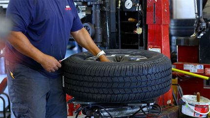 Stack of four tires next to one tire with a silver rim and red brake calipers.