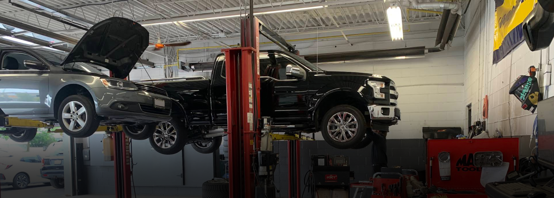 A couple of cars are sitting on a lift in a garage | MechaniQ