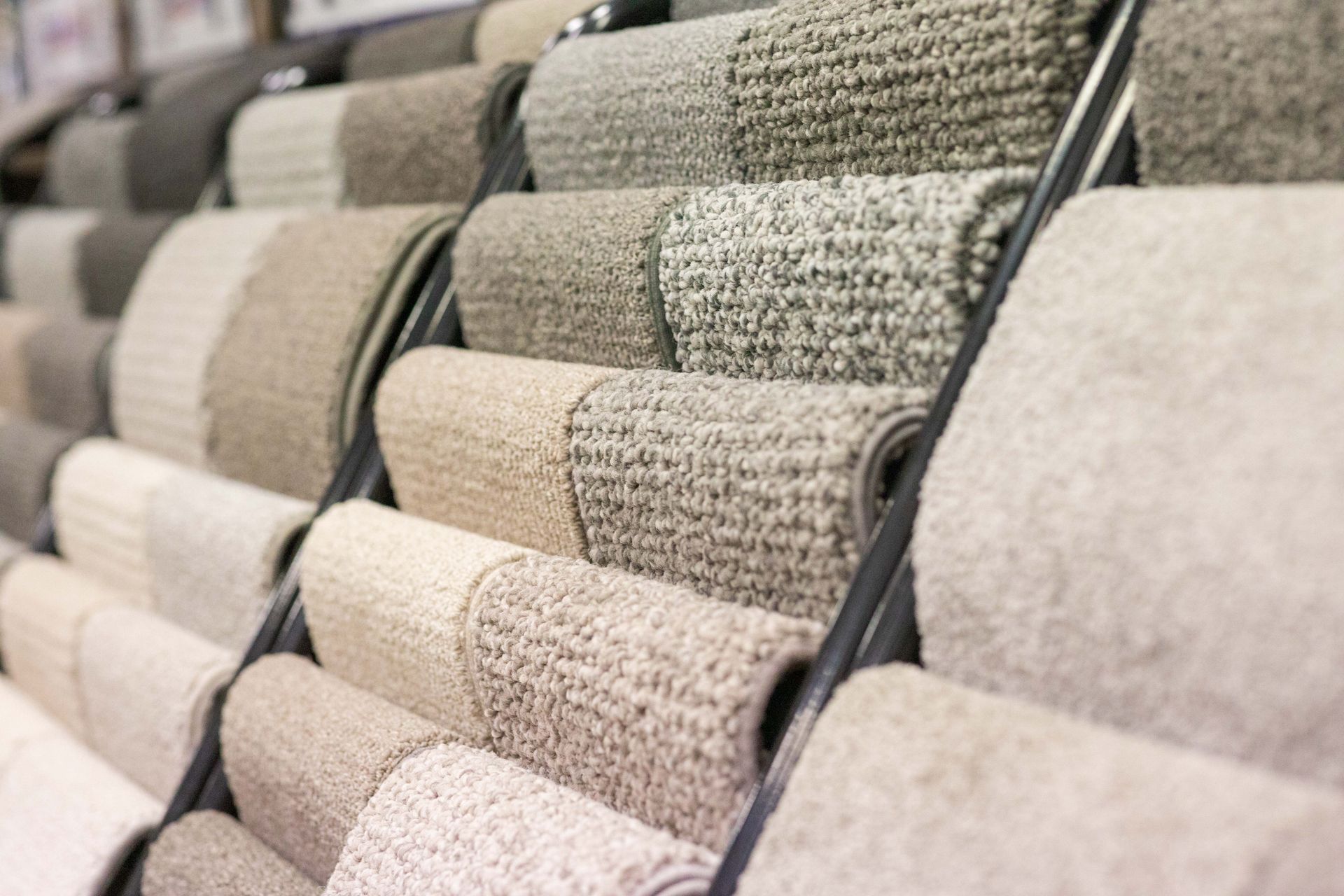 Carpet samples in neutral colours displayed on a rack in a store.