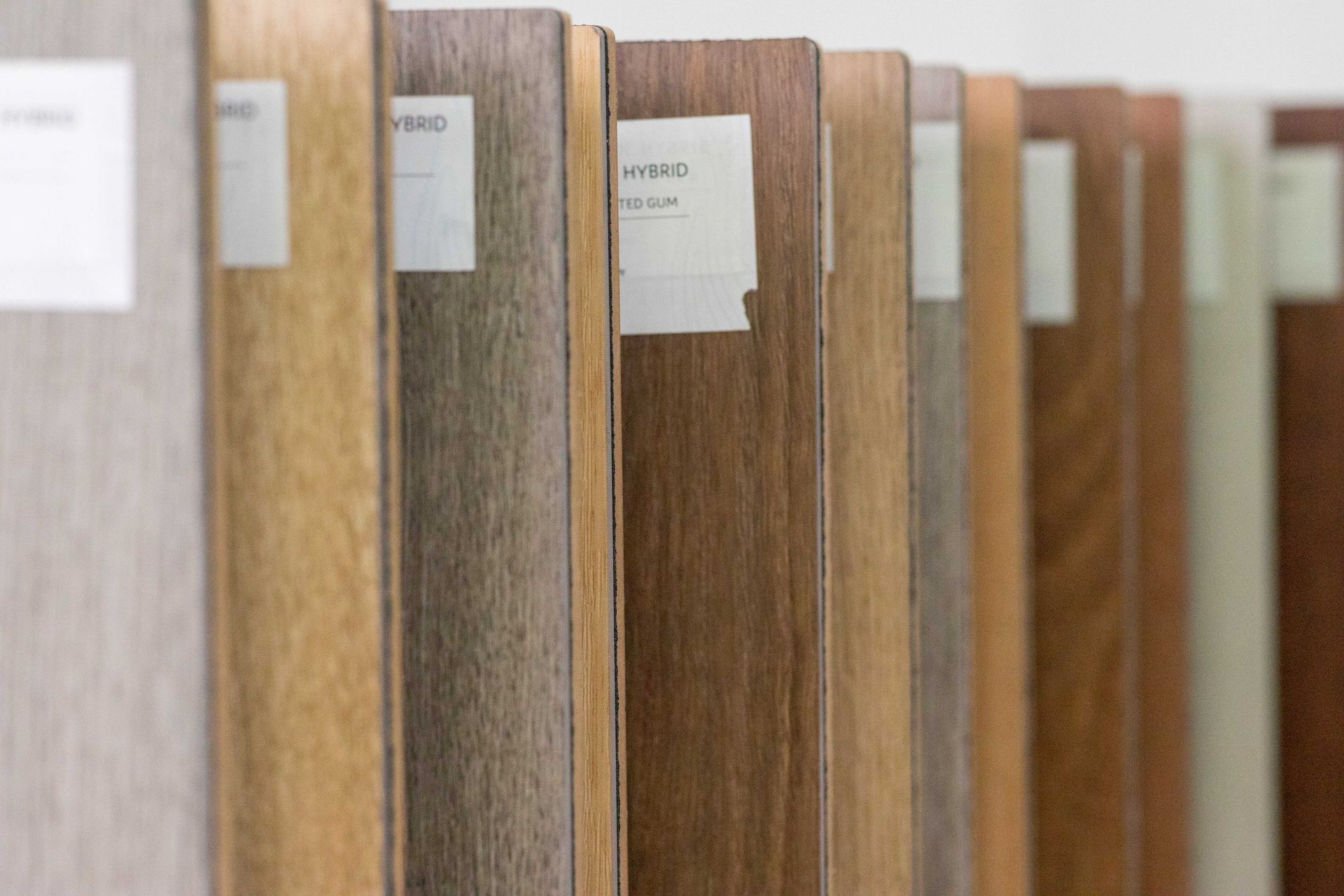 Close-up of various wood flooring samples in different shades, with white labels attached.