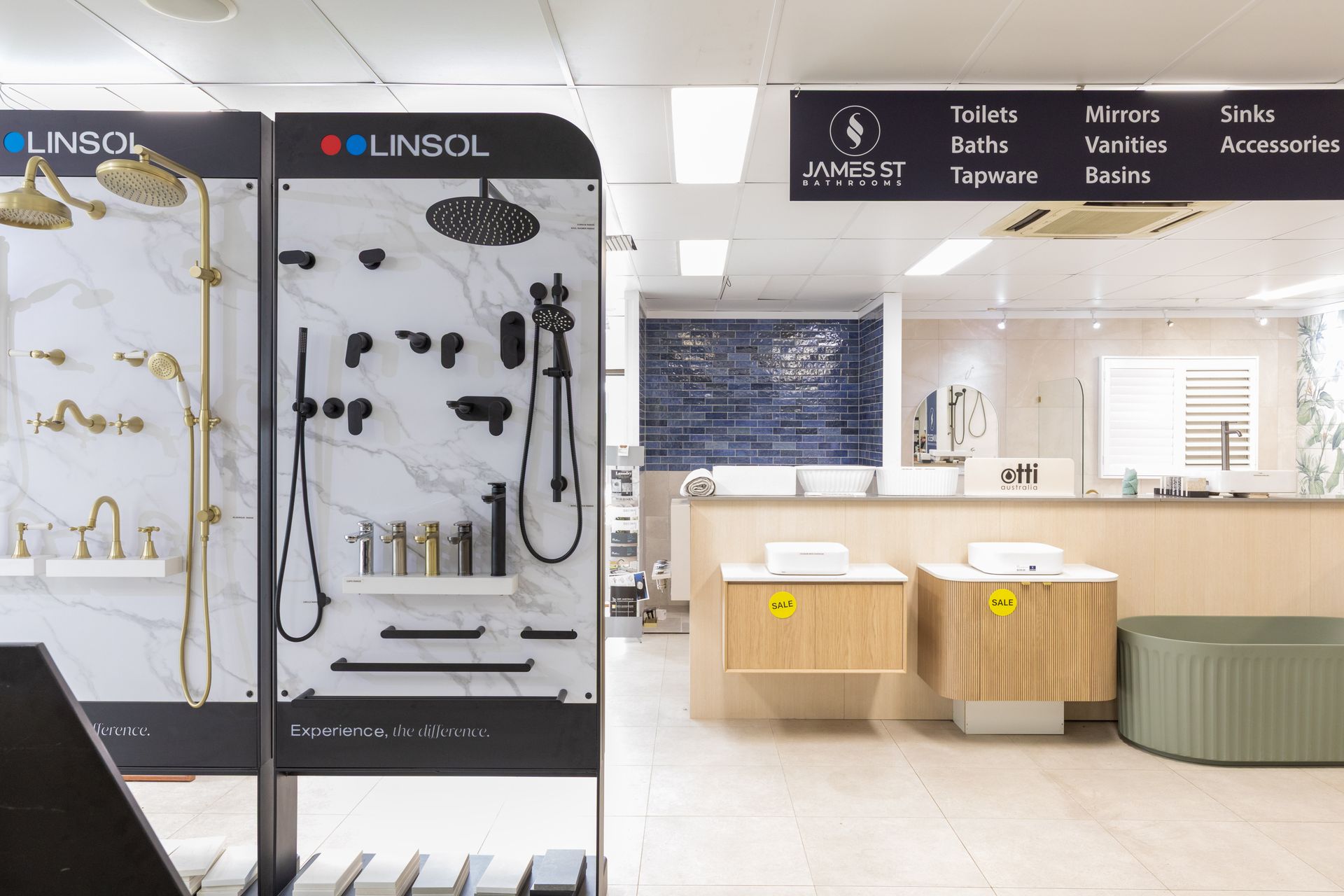 Bathroom showroom with display of shower fixtures, sinks, and tiles.