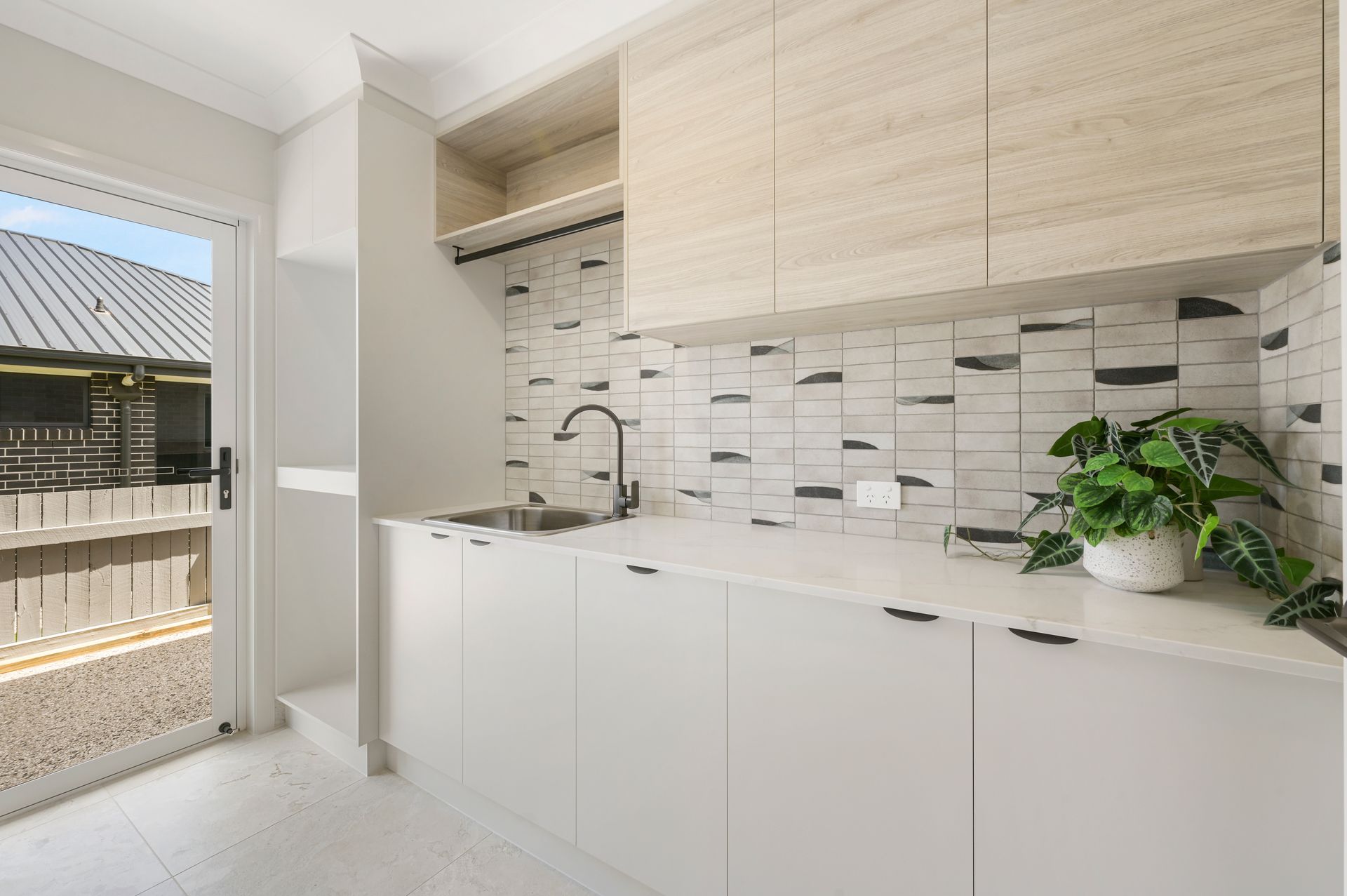 Bright laundry room with white cabinets, a wooden cabinet, and a black faucet.