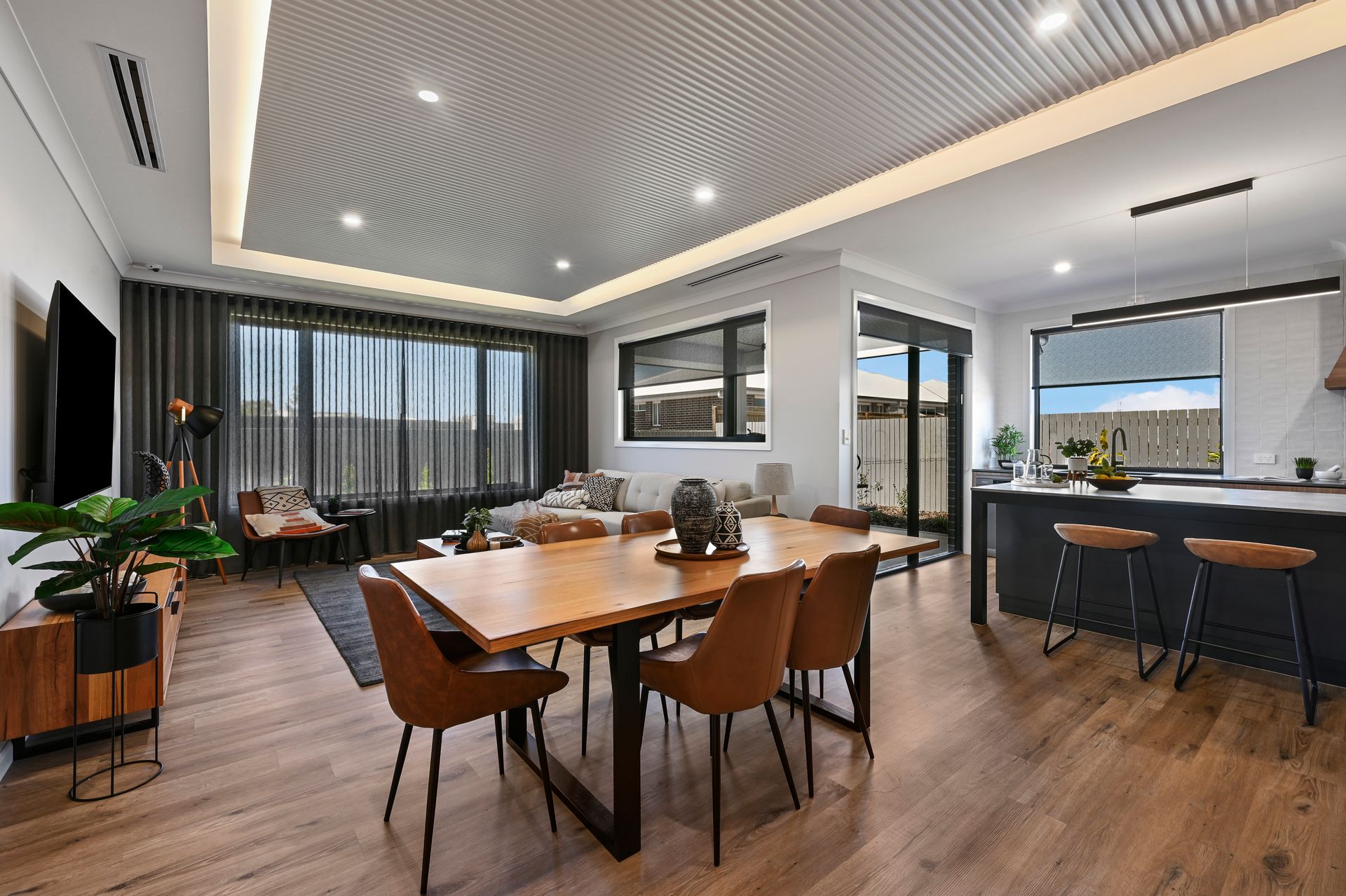 Open-concept dining area with wood table, brown chairs, and accent lighting.