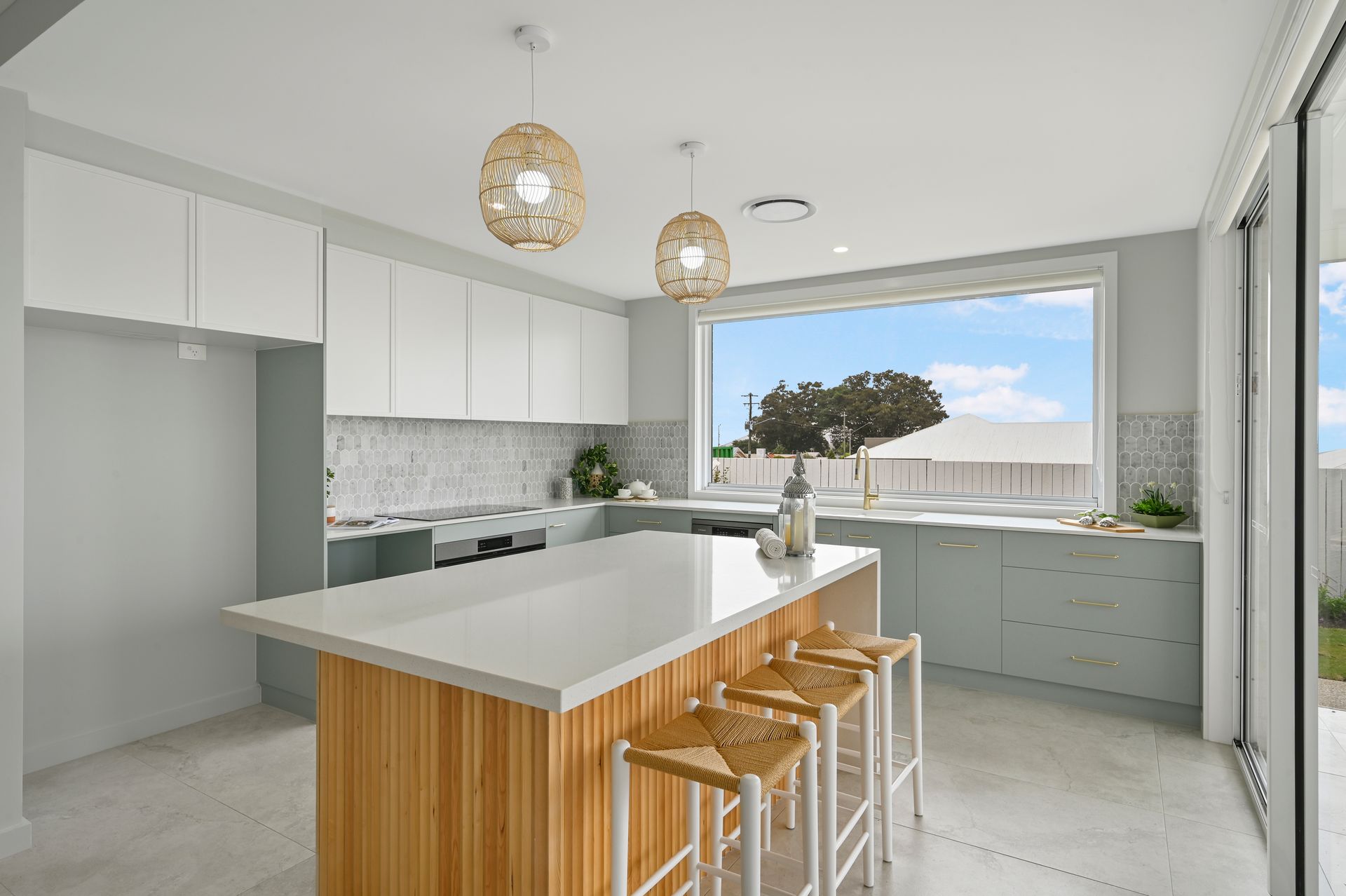 Modern kitchen with light blue cabinets, a wooden island with stools, and a large window.